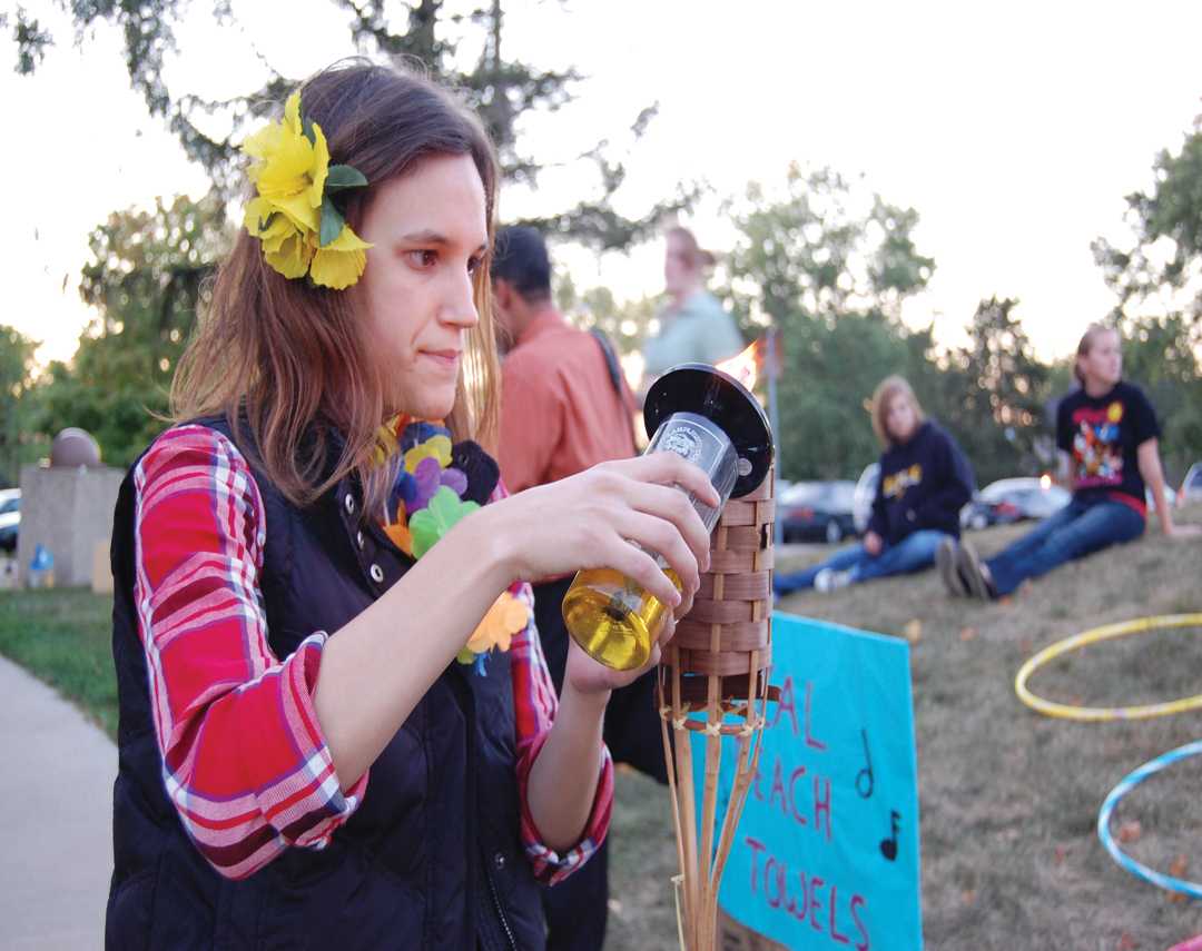 Junior Spanish education major Hannah Corcoran lighting one of the tiki torches on Greenwood Avenue during Wilgus and McGregor Halls’ annual luau Thursday.