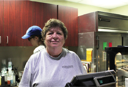 Huehne smiles from behind the register at Hickory & Main, where she has served many students and faculty.