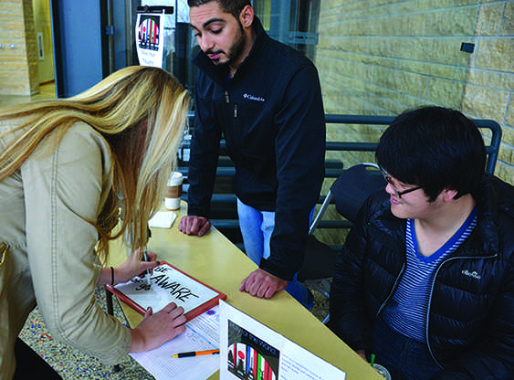 Junior business administration major Sierra Hartman , sophomore computer science major Mohammad AL Shatti  and engineering major Ryan Kim show support for international students and global victims of terrorism.