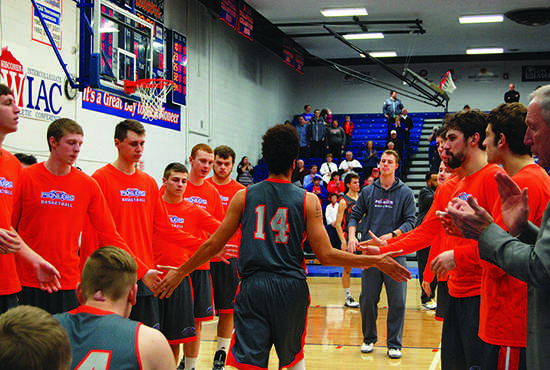 Senior, Boston Johnson slaps the hands of his teammates as he makes his way onto the floor to shake hands with his UW-Lacrosse opponent during the Coaches vs. Cancer game Saturday night.