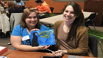 Senior business administration and industrial technology major Jocelyn Key and senior biochemistry and biology major Mallory Jasicki show-off their artwork at Paint and Punch.