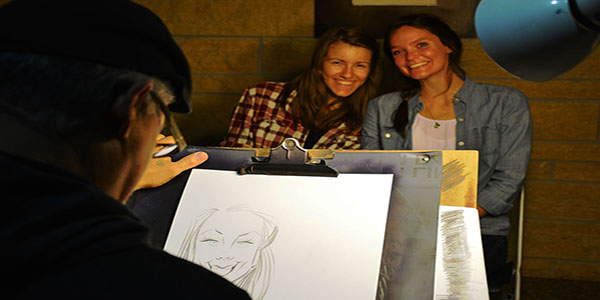 Junior mechanical engineering majors Elisa Broughton and Beth Klein pose for a photo while getting their faces drawn by a charicature artist.