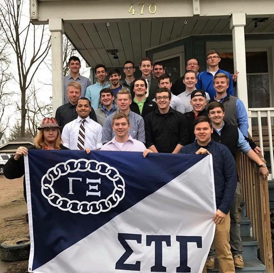 Sigma Tau Gamma members pose together with their fraternity’s flag to show their brotherhood.