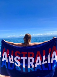 Senior animal science major Jessie Thompson poses with an Australian banner as she over looks the ocean during her study abroad experience. 