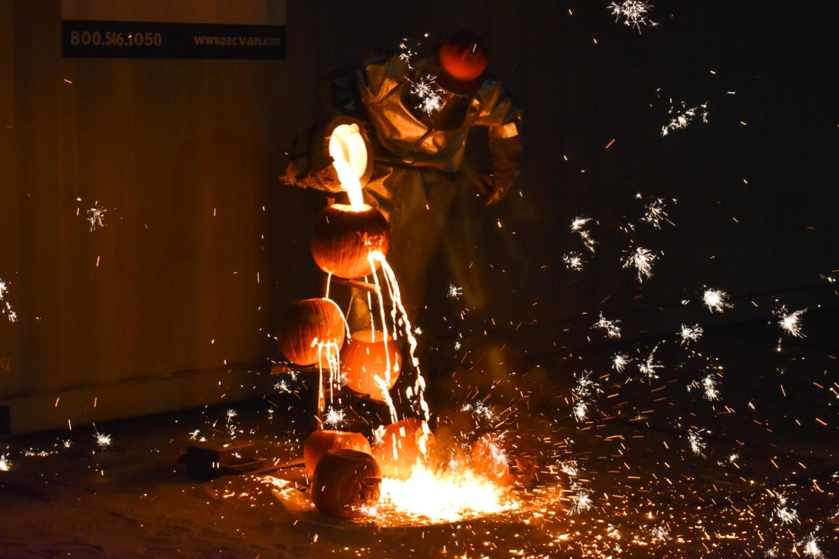 Melting Pumpkin: An AFS member pours hot iron on multipe pumpkins that have been carved, sparking across the pavement.